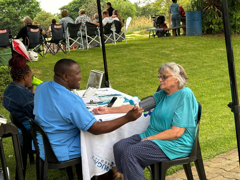 A healthcare worker checking a community member’s blood pressure outdoors