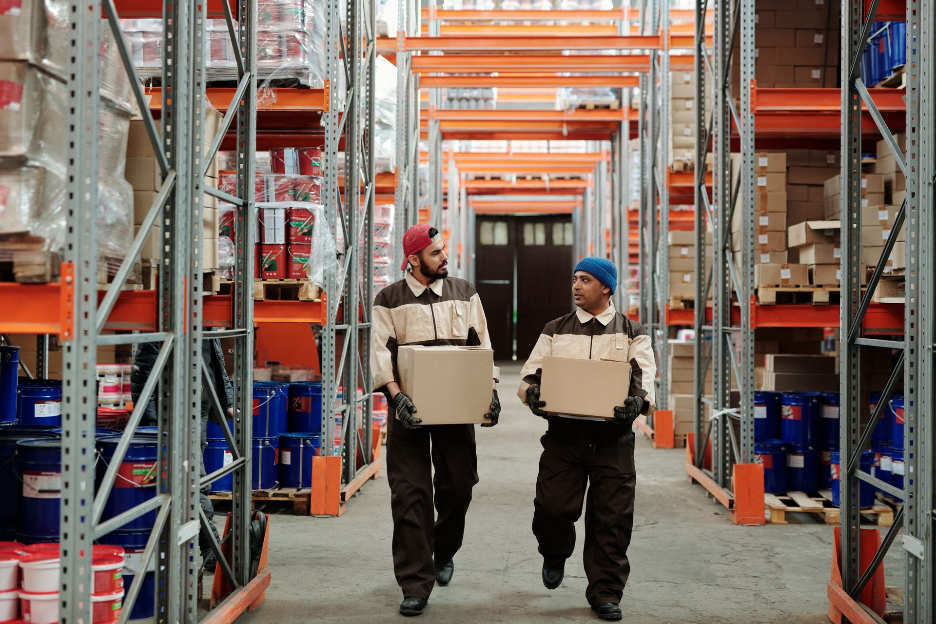 Warehouse workers carrying packaged goods through a storage facility