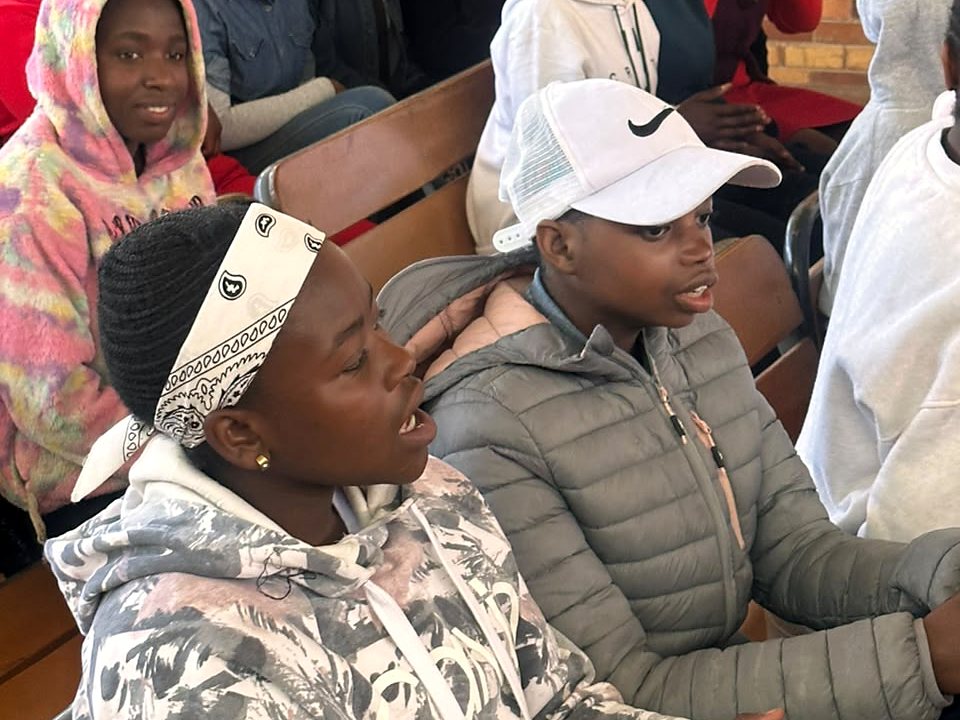 Young community participants seated together during an indoor outreach programme