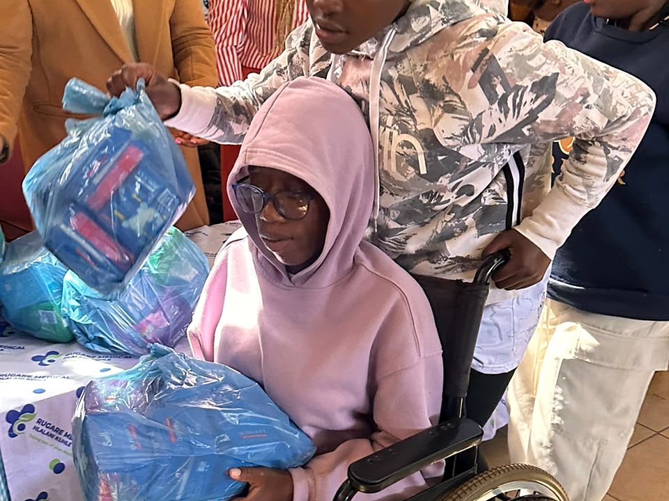 A wheelchair user holding a support package while outreach representatives assist nearby