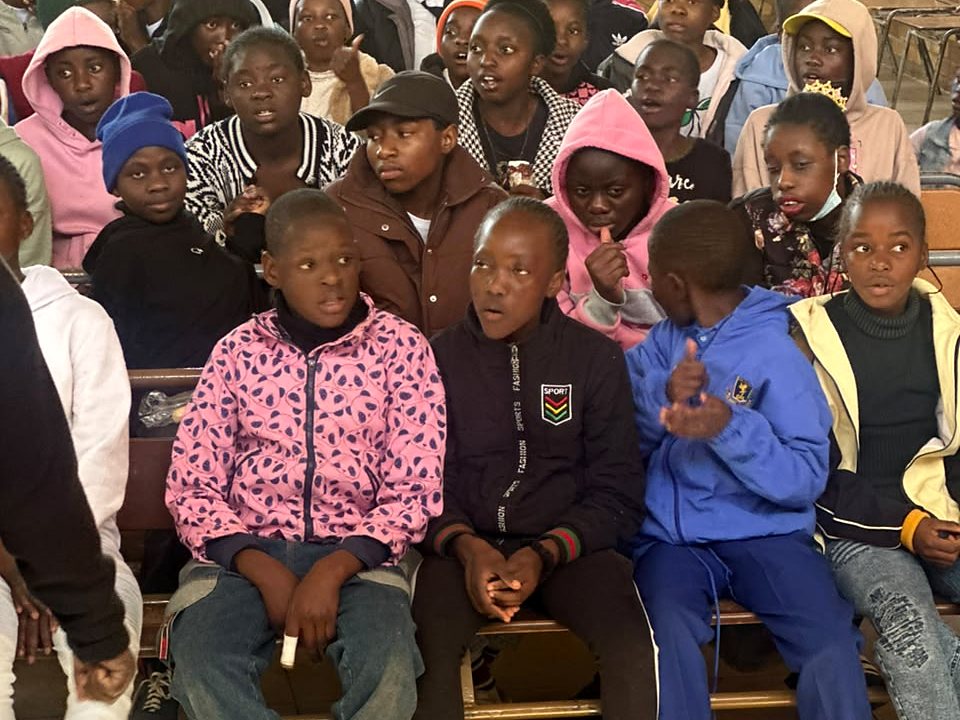 Young participants seated together with packaged supplies in the foreground