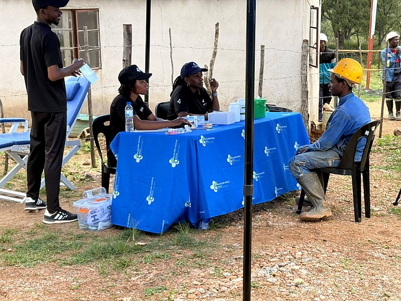 Rugare representatives speaking with a community participant at an outdoor health stand