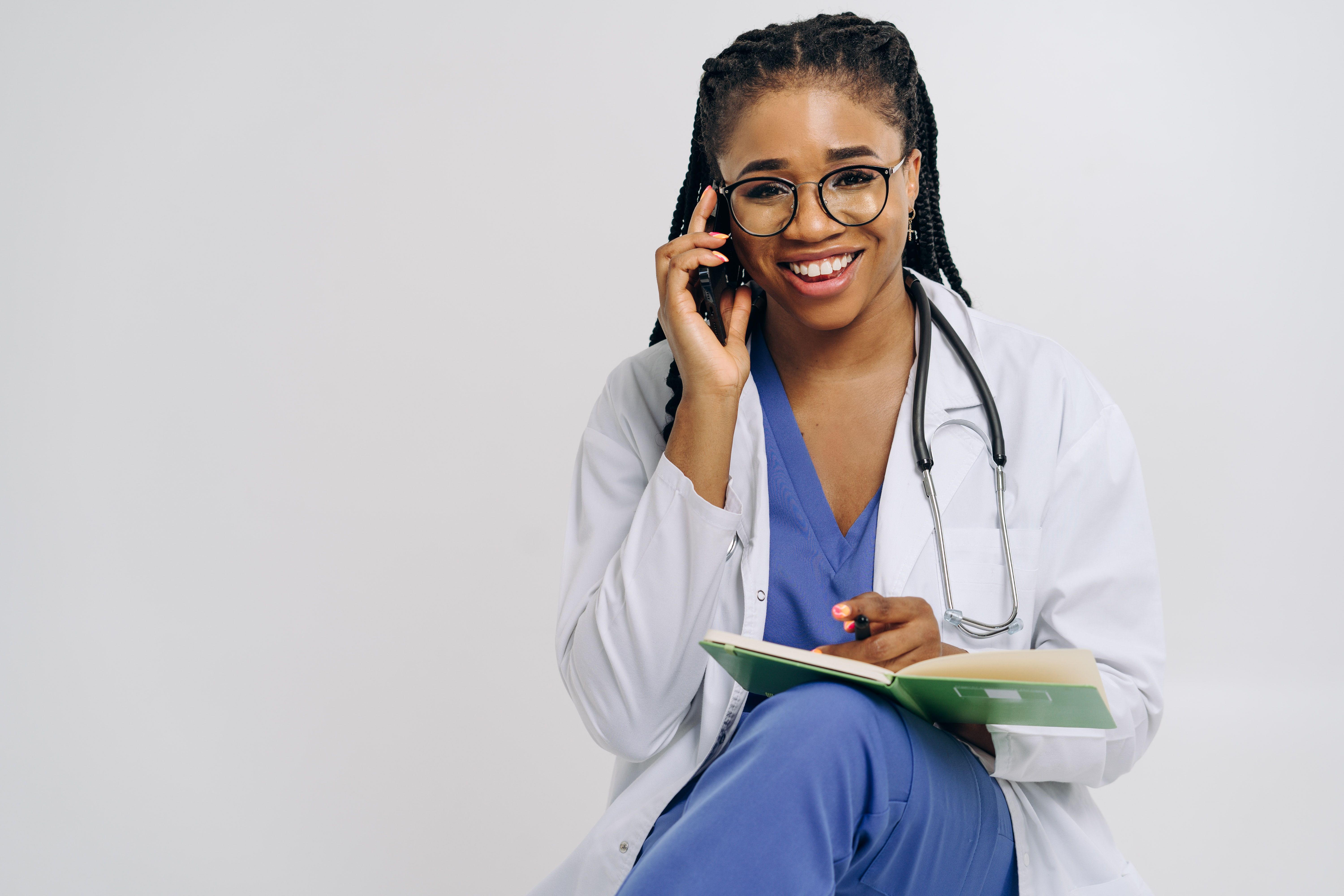 Photo of a doctor taking a phone consultation while reviewing notes, representing physician services